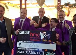 Hugo de Jonge (wethouder van Onderwijs Rotterdam), Jasper Kaarsemaker (docent), Denny Terlouw (locatiedirecteur HMC Rotterdam), docenten Jaap Buitelaar, Dennis van Damme en een HMC-leerling voor het glazen HMC-huis met de waardecheque.  