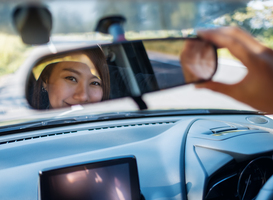 Normal_a-woman-adjusting-a-rear-view-mirror-while-driving-2023-11-27-05-33-45-utc